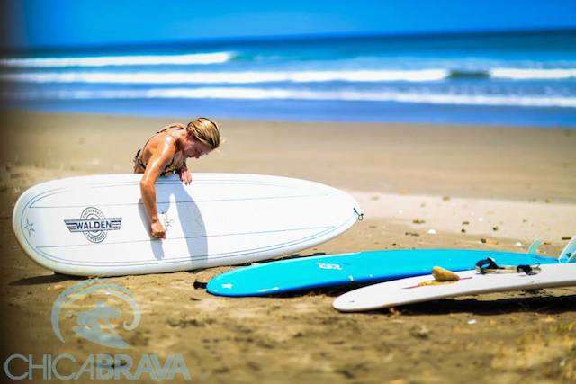 girl putting wax in her surf board on the beach in Nicaragua